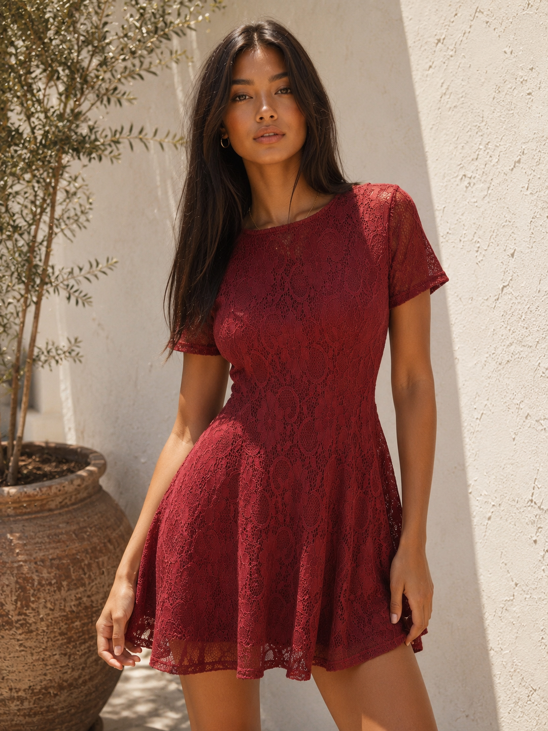 Woman wearing a burgundy floral lace fit and flare mini dress with short sleeves, a round neckline, and a feminine skater silhouette.