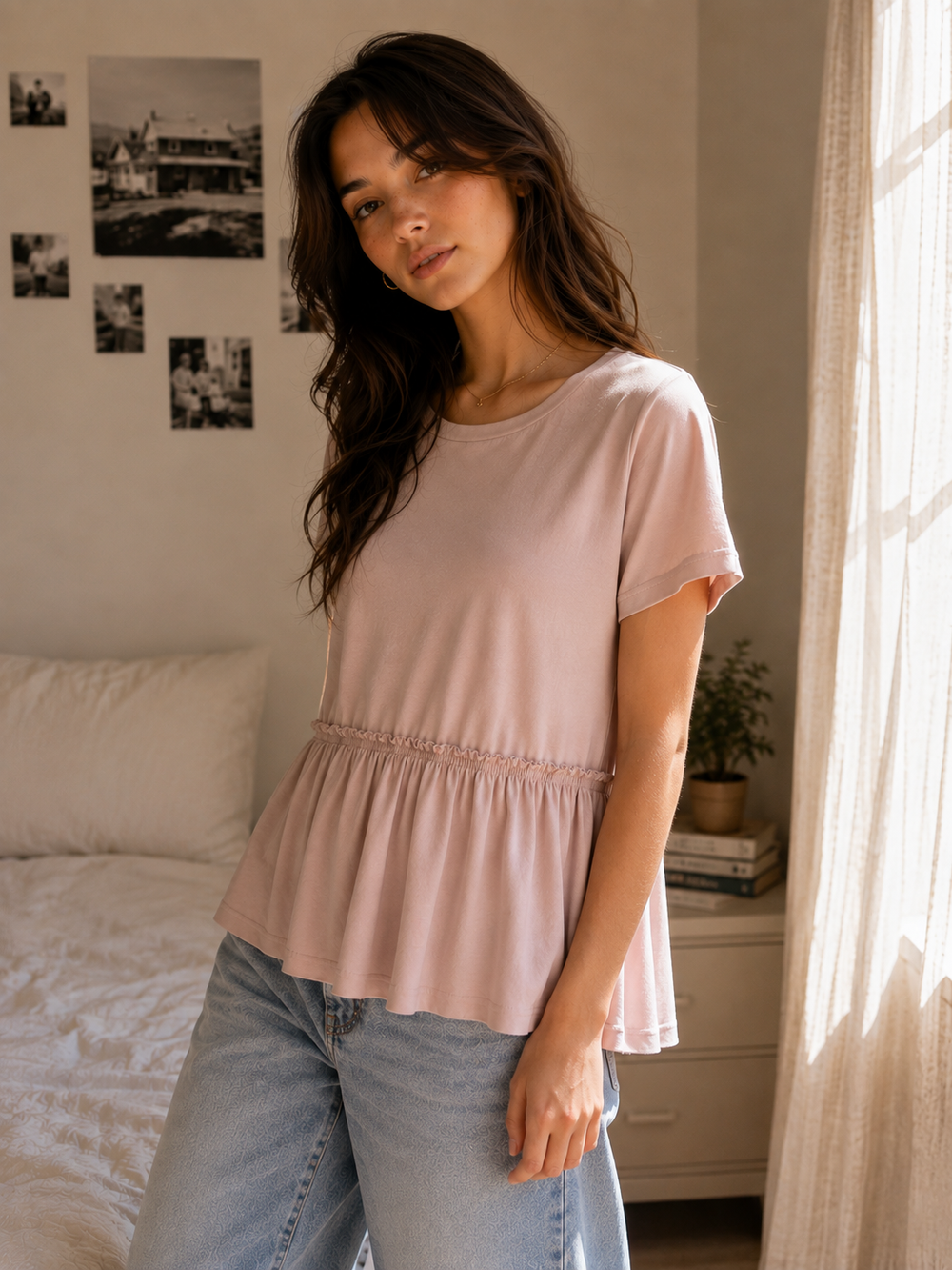 Side view of a blush pink crew neck peplum top featuring a gathered waist and flowy hem.