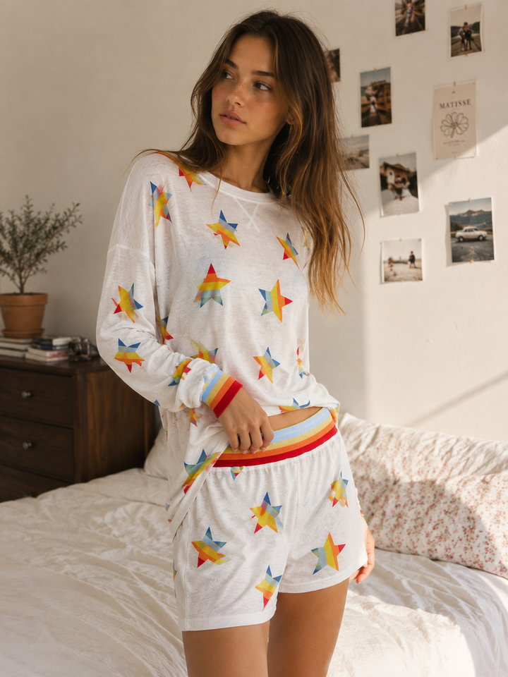 Side view of the rainbow star print lounge set with striped ribbed waistband and cuffs.