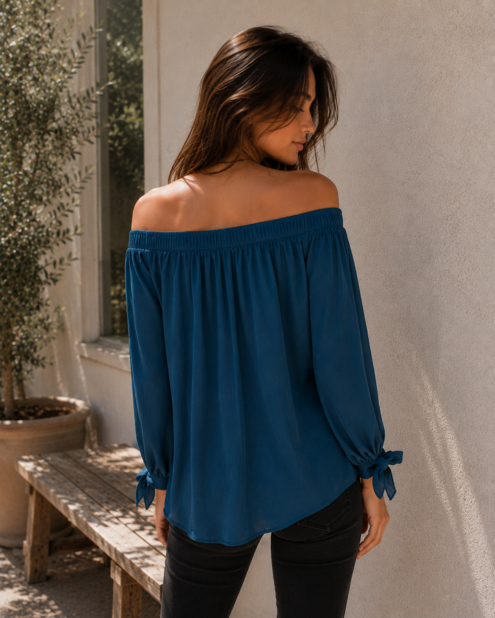 Back view of teal off-the-shoulder long sleeve blouse with tie cuffs.