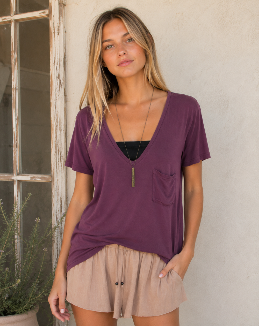 Woman wearing an olive oversized V-neck pocket tee with casual lounge shorts.