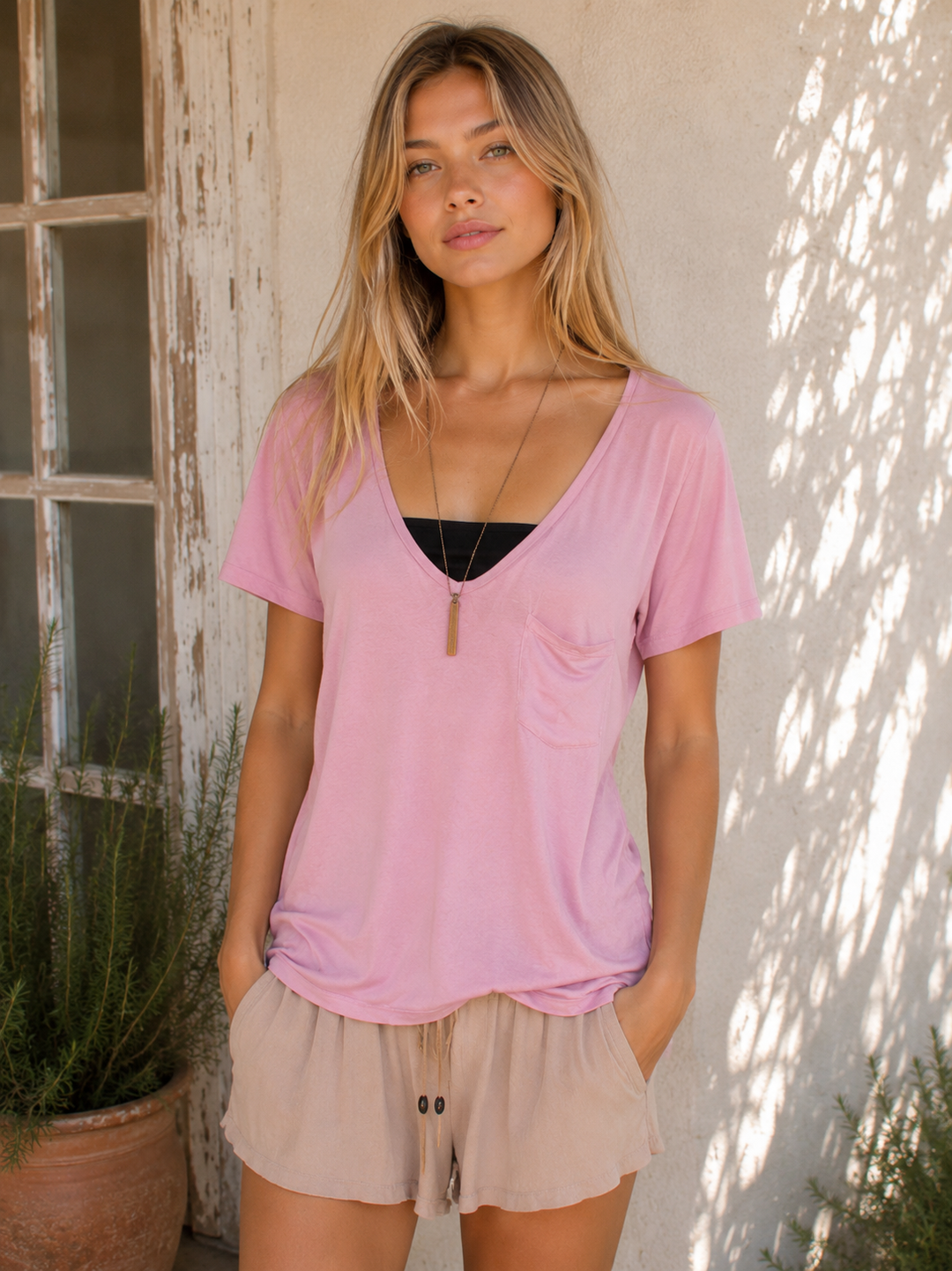 Woman wearing a pink oversized soft V-neck T-shirt paired with lightweight drawstring shorts.