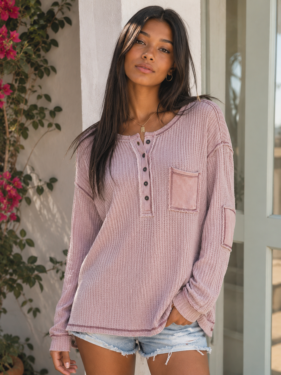 Women's dusty mauve waffle knit Henley tunic featuring a relaxed oversized fit, button neckline, exposed seam detailing, chest pocket, long sleeves, and high-low hem.
