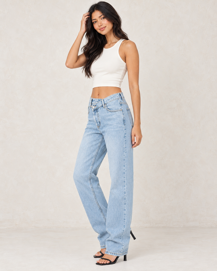 Side view of light-wash asymmetrical wrap-waist denim jeans, showing the loose straight-leg silhouette.