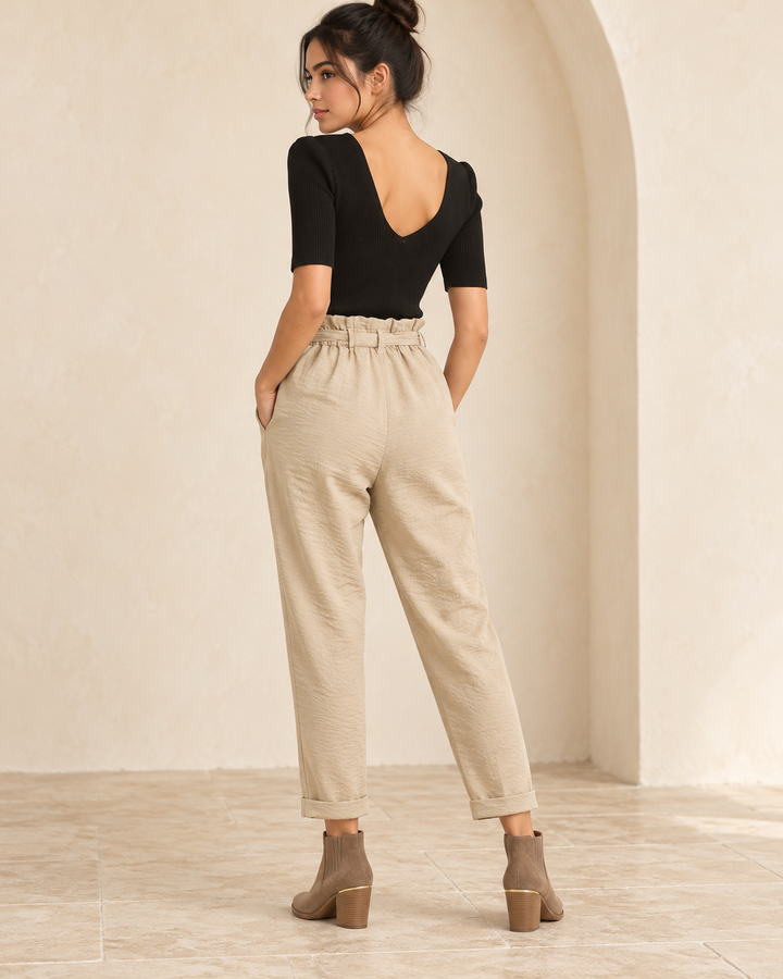Wishlist Beatrice black ribbed bodysuit, back view on a model showing the low rounded V-back with beige linen pants and taupe ankle boots. 