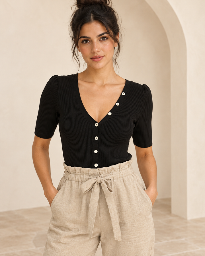 Wishlist Beatrice black ribbed bodysuit, front view on a model showing the button-front V-neck and half sleeves with beige tie-waist linen pants. 