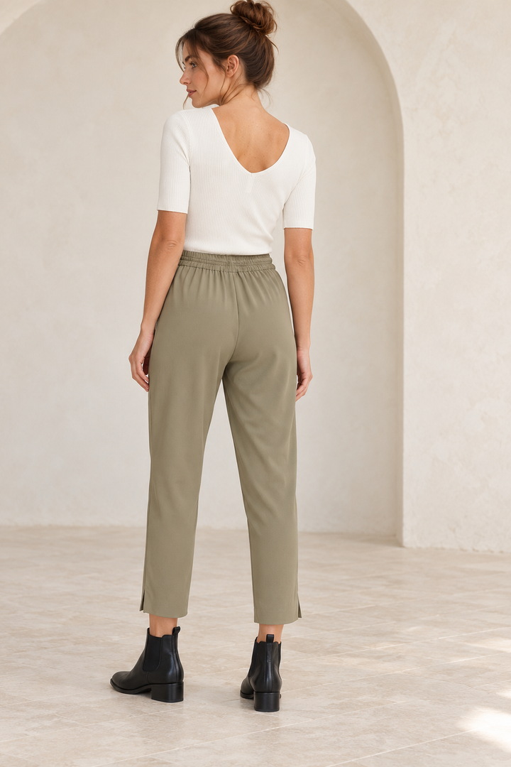 Wishlist Beatrice cream ribbed bodysuit, back view on a model showing the low rounded V-back with olive crepe pants and black Chelsea ankle boots. 