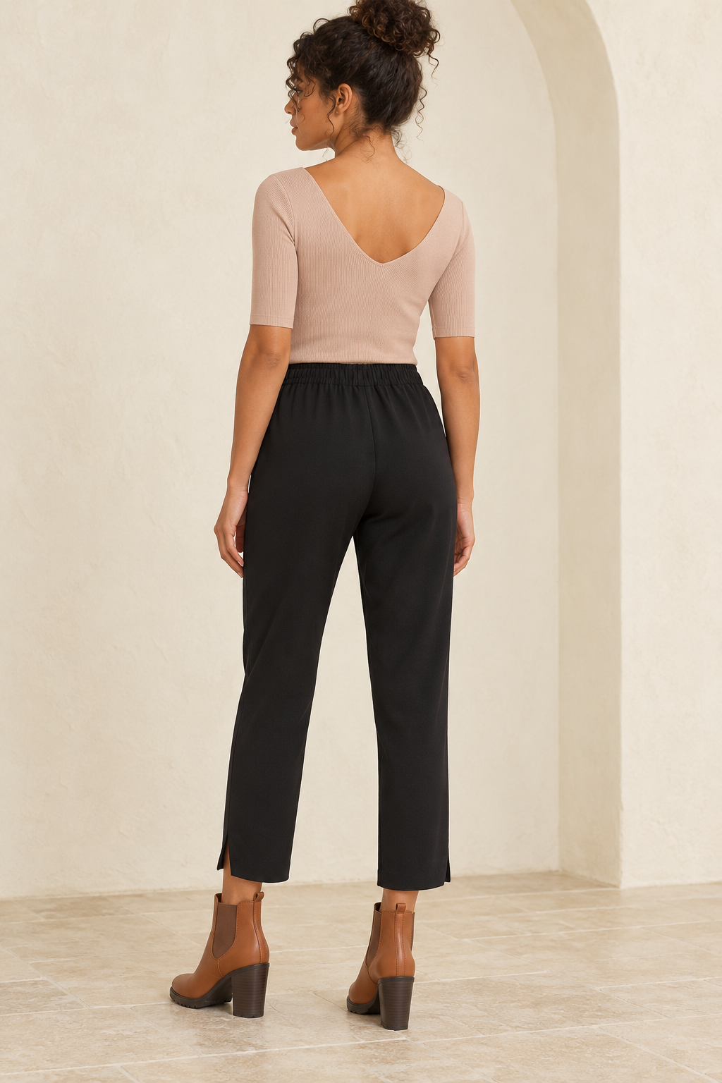Wishlist Beatrice taupe ribbed bodysuit, back view on a model showing the low rounded V-back with black crepe pants and camel Chelsea ankle boots. 