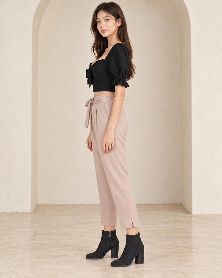 Distraction black bustier cropped blouse, side outfit view showing the puff sleeve and cropped hem, styled with mauve tie-waist pants and black nubuck ankle boots.