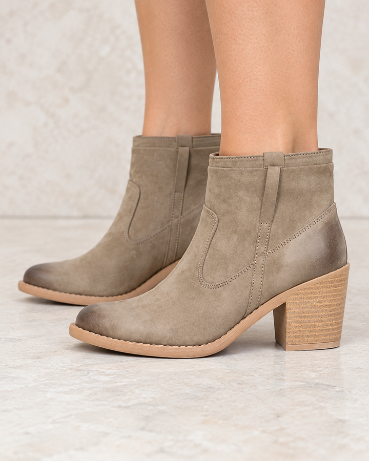 Faux suede taupe ankle boots worn on feet, side view