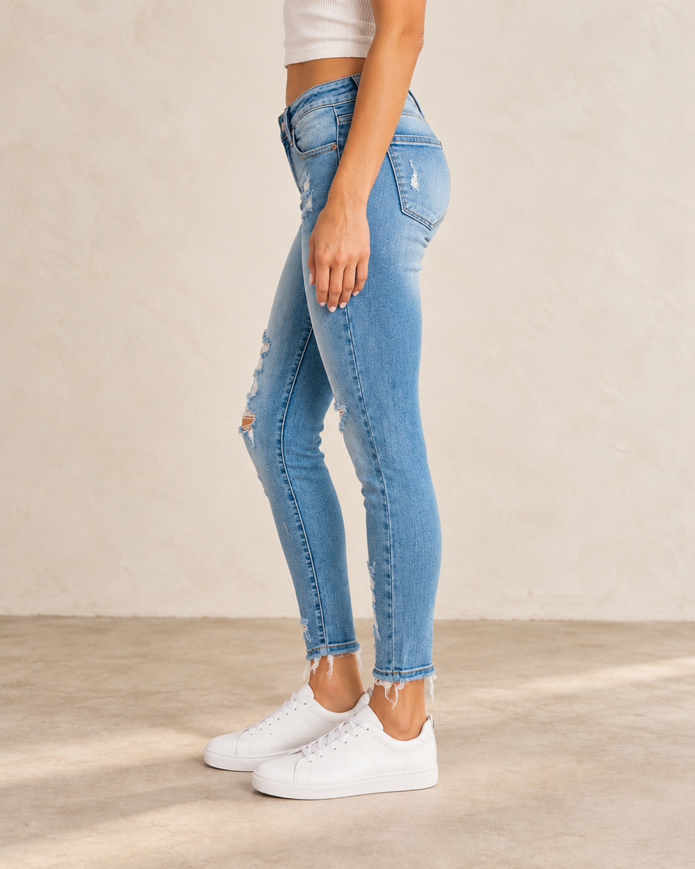 Side view of Lizzy distressed light-wash skinny jeans on a model, showing the slim leg and ankle-length hem.