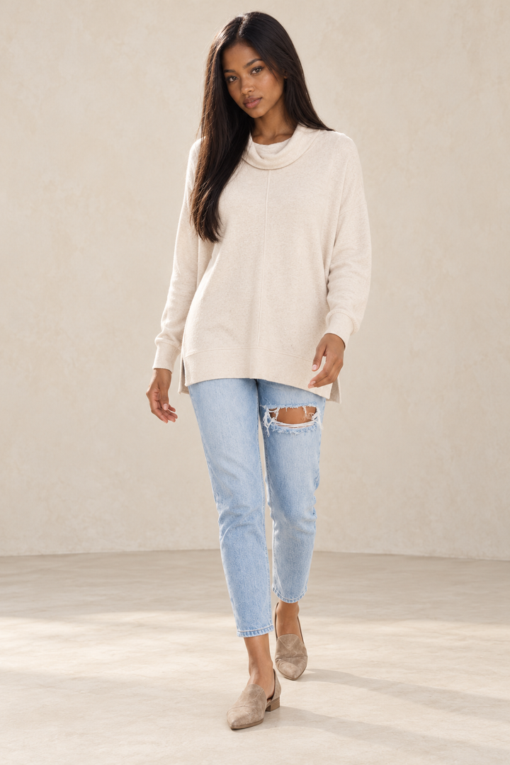 Hattie oatmeal cowl-neck Hacci sweater on a model with light-wash distressed mom jeans and taupe pointed-toe flats.