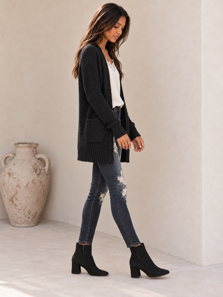 Side view of the black fuzzy pocketed open-front cardigan showing the long sleeve and soft fuzzy texture.