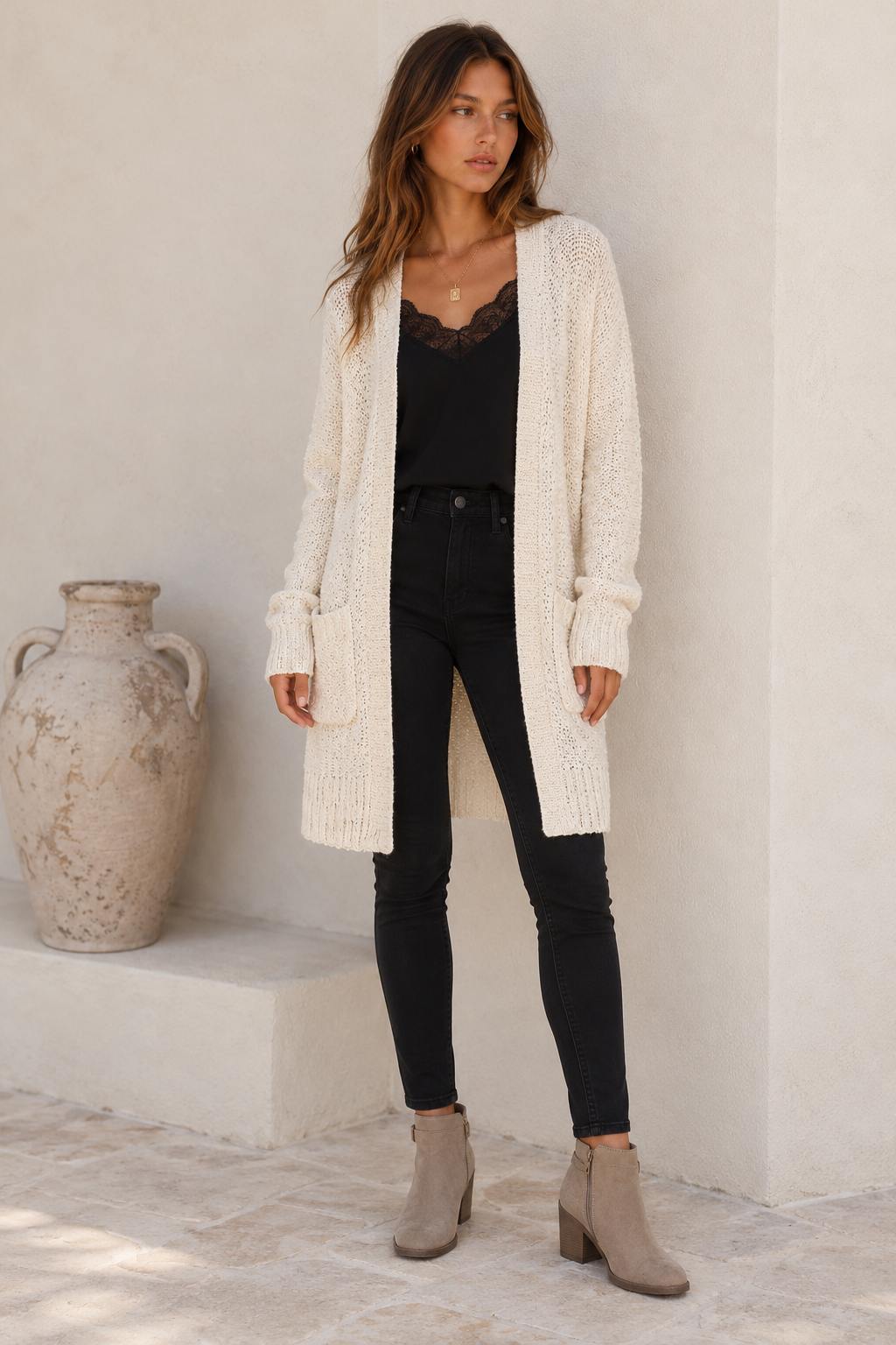 Front view of the cream open-front longline cardigan, styled with a black lace camisole, black slim denim and taupe ankle boots.