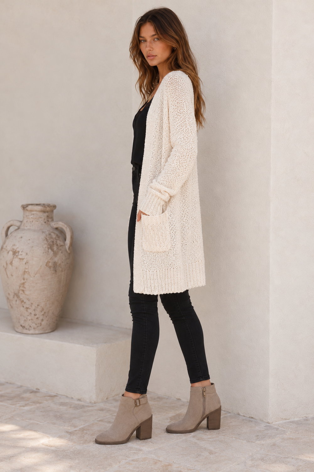 Side view of the cream longline cardigan, showing the open front, patch pocket, long sleeves and textured knit.