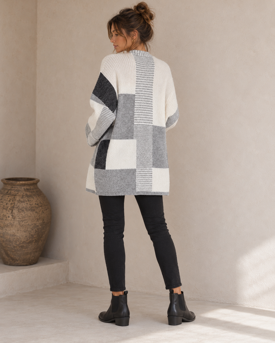 Back view of the greyscale cardigan showing the center stripe column and asymmetric grey, charcoal and ivory panels.