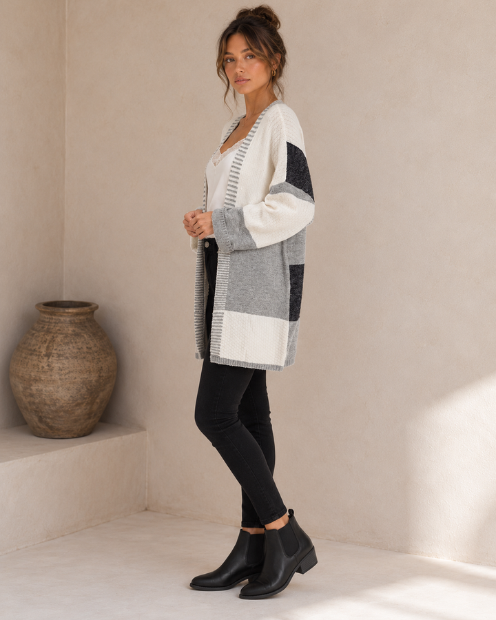 Side view of the greyscale longline cardigan showing its dropped shoulder, charcoal sleeve panel and relaxed hem.
