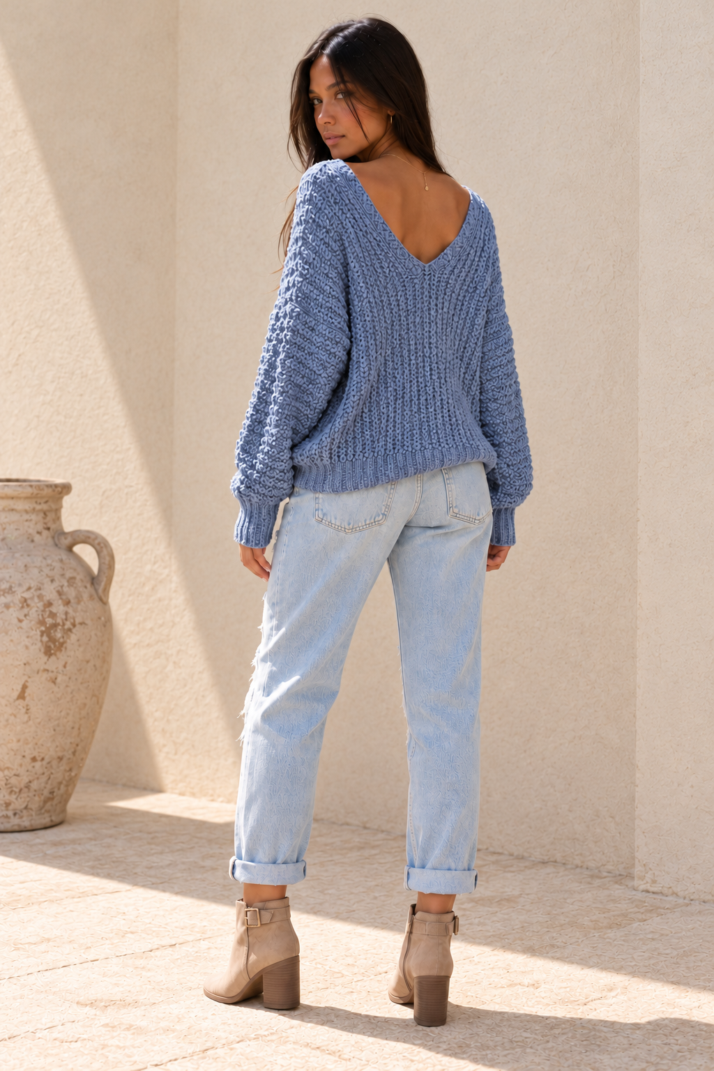 Back view of the misty-blue popcorn-knit sweater, showing the wide V-back neckline and relaxed shape.