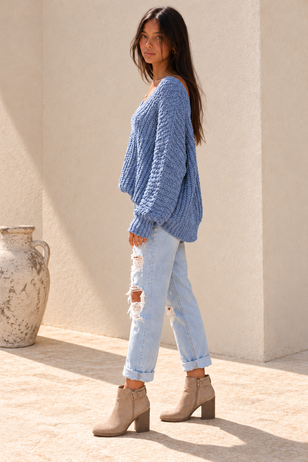 Side view of the misty-blue popcorn-knit sweater, showing the relaxed fit, long sleeves and ribbed cuffs.