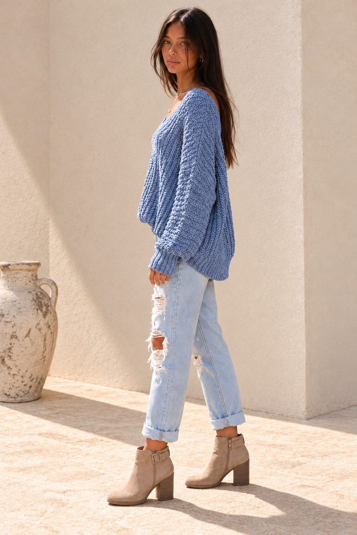 Side view of the misty-blue popcorn-knit sweater, showing the relaxed fit, long sleeves and ribbed cuffs.