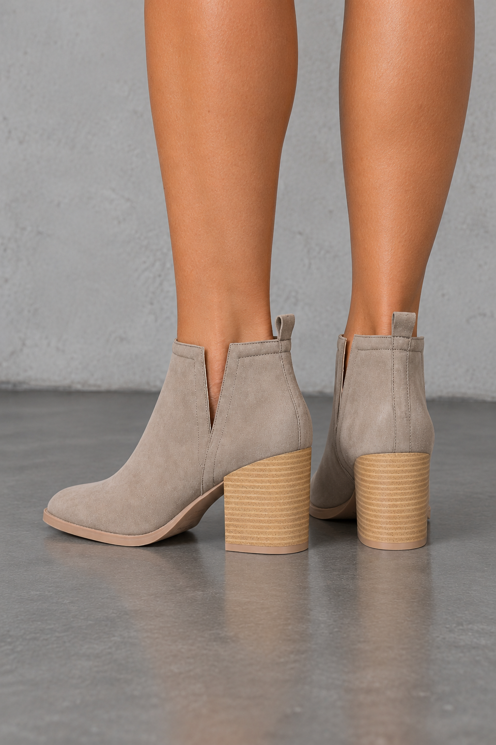 Taupe side-slit Chelsea ankle booties with stacked-look heels, back view worn on feet in a neutral studio.