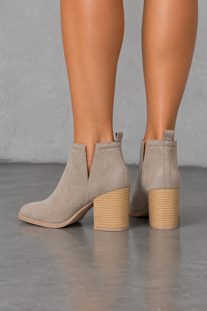 Taupe side-slit Chelsea ankle booties with stacked-look heels, back view worn on feet in a neutral studio.