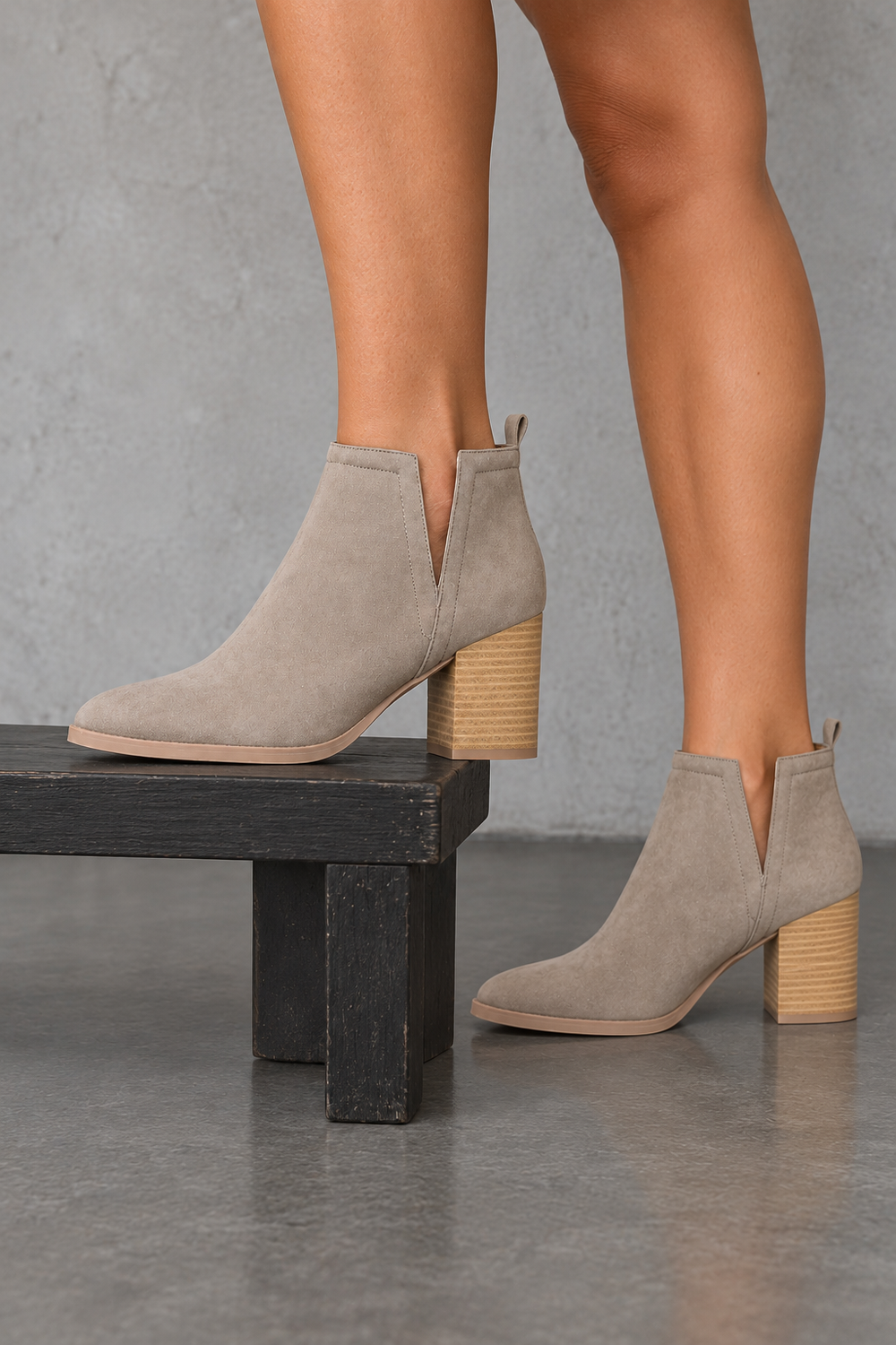 Taupe side-slit Chelsea ankle booties with stacked-look heels, side view worn on feet in a neutral studio.