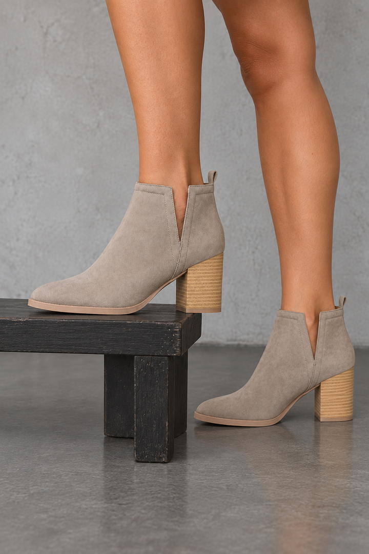 Taupe side-slit Chelsea ankle booties with stacked-look heels, side view worn on feet in a neutral studio.