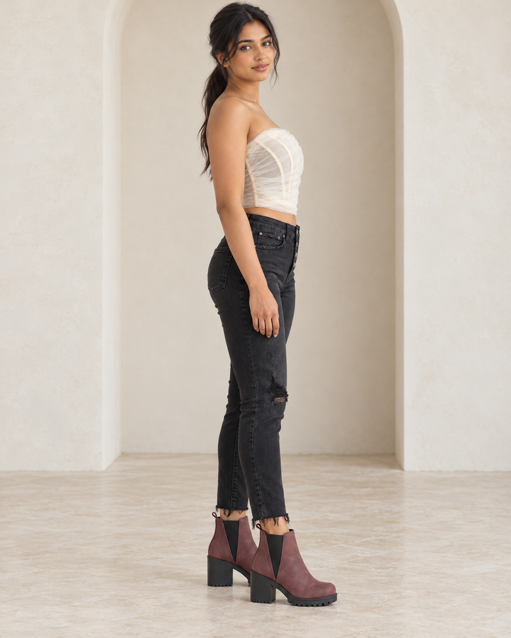 Willow bone strapless tulle corset top, side outfit view showing structured seams and draped tulle, styled with black skinny jeans and wine platform ankle boots.