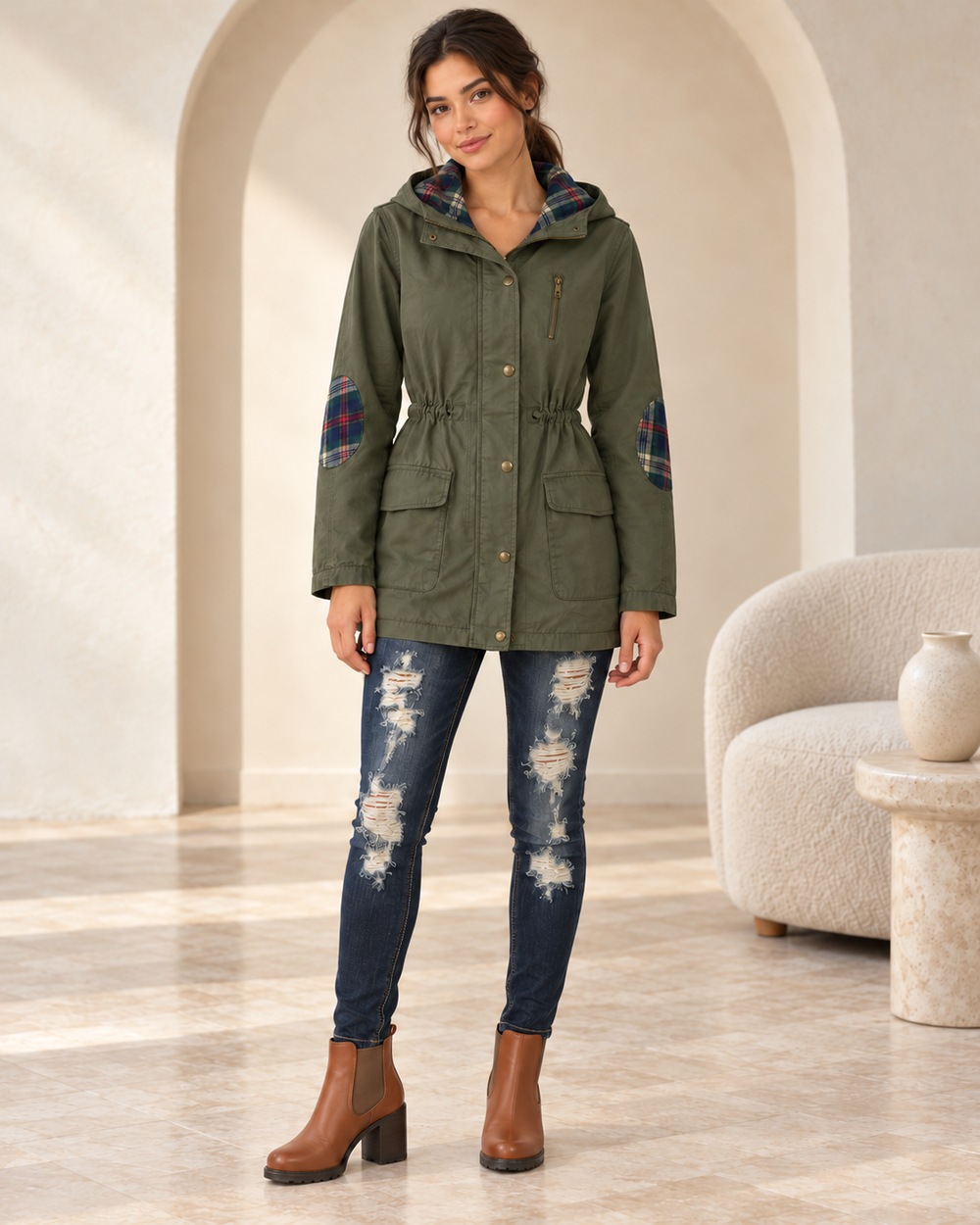 Olive hooded utility parka on an adult model, closed-front view showing the drawstring waist and flap pockets.
