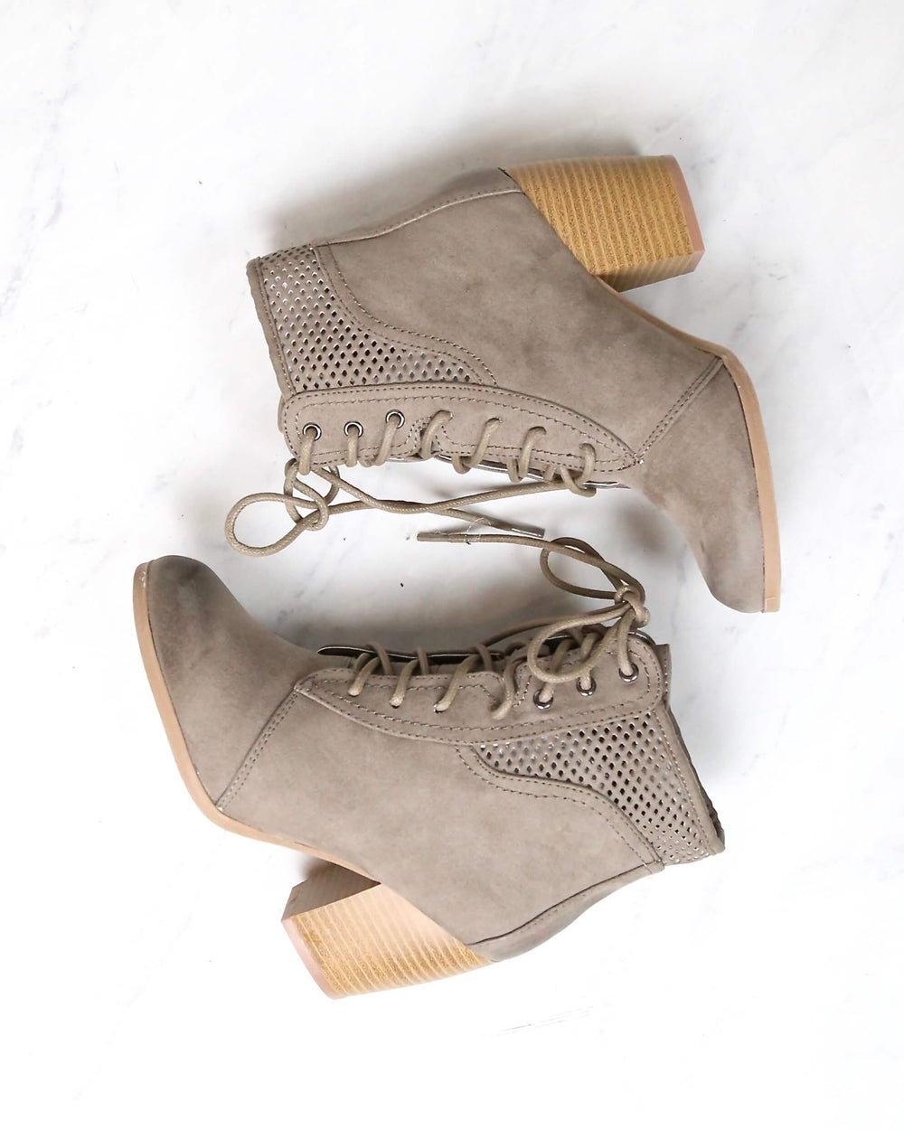 Taupe Point the Way lace-up booties laid on their sides showing perforated panels